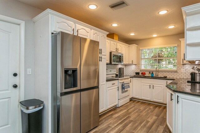 4021 Vana Dr, Sarasota, FL 34241 - kitchen with stainless steel appliances, a sink, dark wood-style floors, white cabinetry, and tasteful backsplash