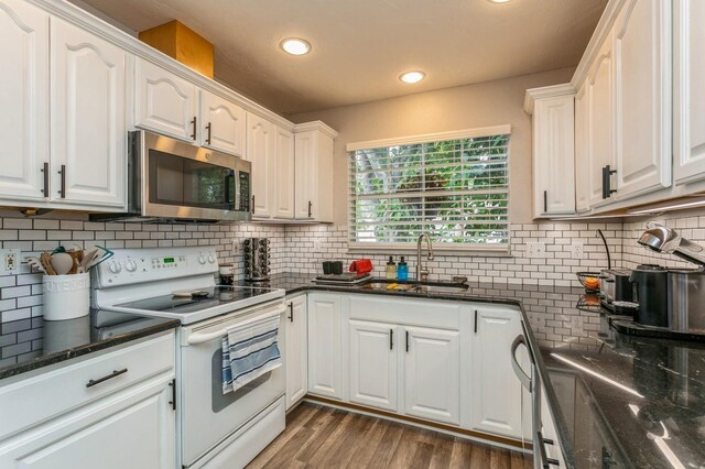 4021 Vana Dr, Sarasota, FL 34241 - kitchen with white electric range, stainless steel microwave, a sink, white cabinets, and backsplash