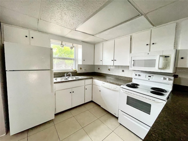 72 Lake Shore Dr, Palm Harbor, FL 34684 - kitchen with white appliances, a drop ceiling, dark countertops, white cabinets, and light tile patterned floors