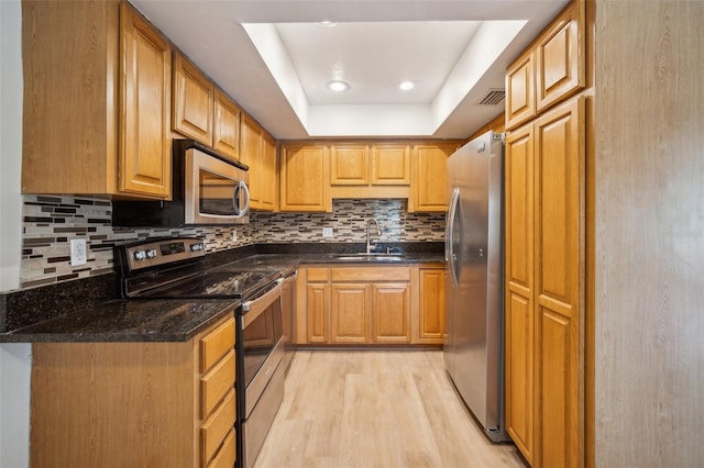 15202 Morning Dr, Lutz, FL 33559 - kitchen featuring appliances with stainless steel finishes, a sink, light wood finished floors, tasteful backsplash, and a tray ceiling