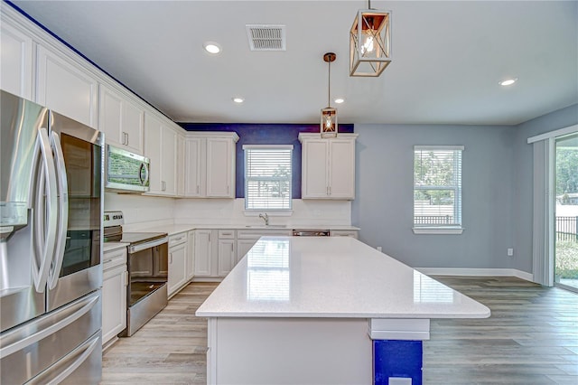 6119 Bradford Woods Dr, Zephyrhills, FL 33542 - kitchen with stainless steel appliances, a sink, light wood-style flooring, a center island, and recessed lighting