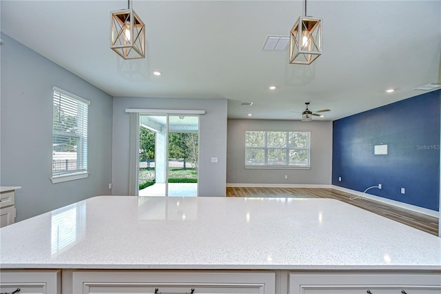 6119 Bradford Woods Dr, Zephyrhills, FL 33542 - kitchen featuring light stone countertops, open floor plan, white cabinets, ceiling fan, and recessed lighting