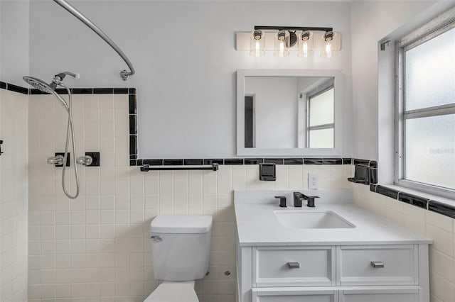 1412 Coburn Dr, Tarpon Springs, FL 34689 - bathroom featuring tiled shower, vanity, toilet, tile walls, and a wainscoted wall
