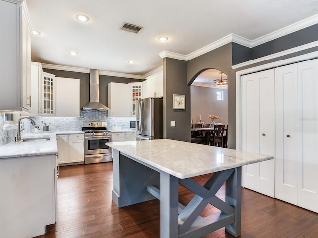 3003 W Leila Ave, Tampa, FL 33611 - kitchen featuring stainless steel appliances, wall chimney range hood, a sink, backsplash, and arched walkways