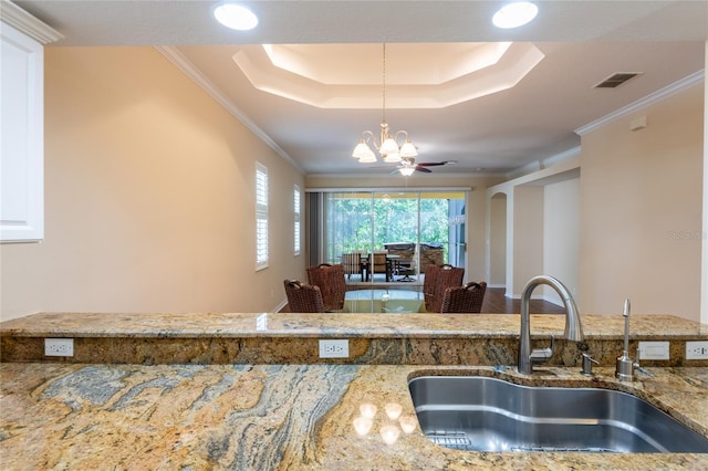 21209 Diamonte Dr, Land O Lakes, FL 34637 - kitchen with a sink, a raised ceiling, a chandelier, light stone counters, and decorative light fixtures