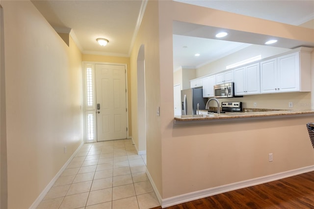 21209 Diamonte Dr, Land O Lakes, FL 34637 - kitchen with stainless steel appliances, ornamental molding, white cabinets, light stone countertops, and baseboards