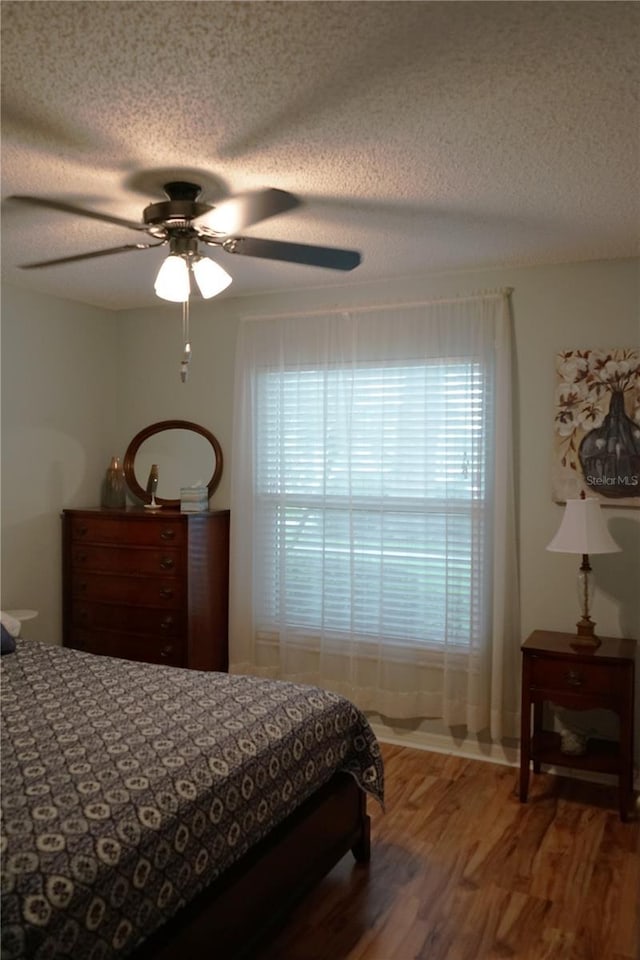 311 Kelsey Way Unit 3, Sun City Center, FL 33573 - bedroom featuring a textured ceiling, wood finished floors, multiple windows, and ceiling fan