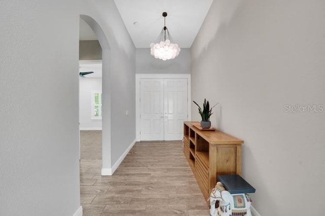 14223 Lambert Bridge Ln, Lithia, FL 33547 - foyer entrance with arched walkways, a chandelier, baseboards, and light wood-style floors