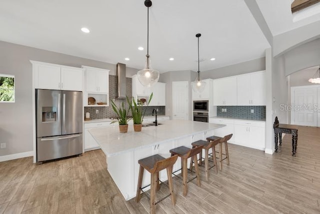 14223 Lambert Bridge Ln, Lithia, FL 33547 - kitchen with stainless steel appliances, wall chimney range hood, decorative backsplash, light wood-type flooring, and light countertops