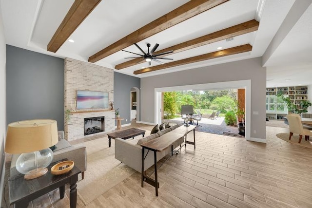 14223 Lambert Bridge Ln, Lithia, FL 33547 - living room with ceiling fan, beamed ceiling, a brick fireplace, baseboards, and light wood-type flooring