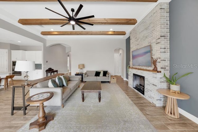 14223 Lambert Bridge Ln, Lithia, FL 33547 - living room featuring arched walkways, beamed ceiling, ceiling fan, a brick fireplace, and wood finished floors