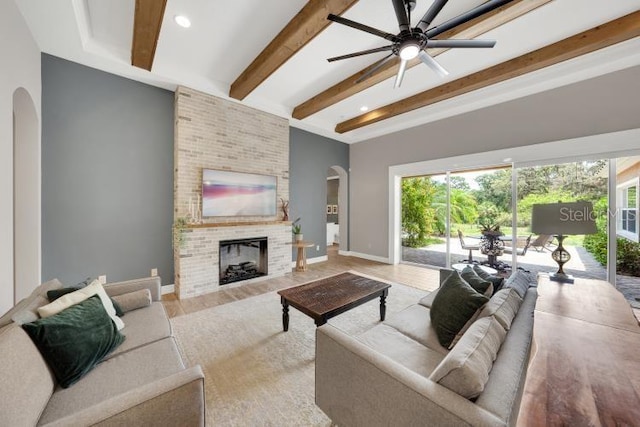 14223 Lambert Bridge Ln, Lithia, FL 33547 - living area with arched walkways, a fireplace, beamed ceiling, a ceiling fan, and baseboards