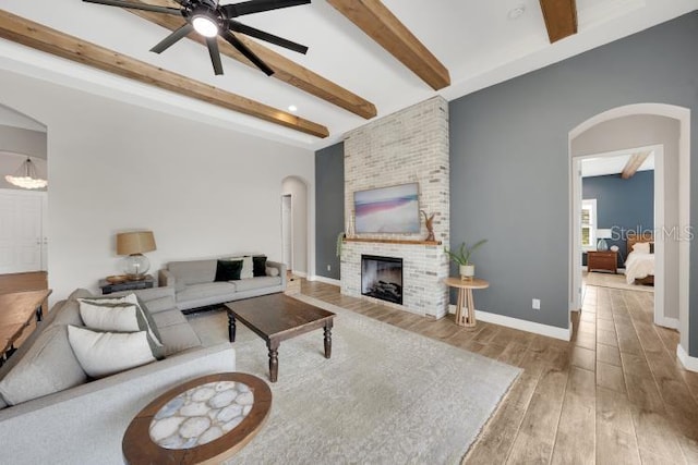 14223 Lambert Bridge Ln, Lithia, FL 33547 - living area with arched walkways, beam ceiling, ceiling fan, a brick fireplace, and wood finished floors