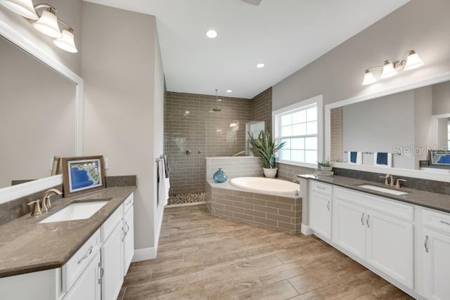 14223 Lambert Bridge Ln, Lithia, FL 33547 - bathroom with two vanities, a walk in shower, a bath, wood finished floors, and recessed lighting