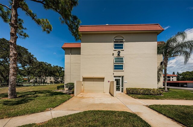 2700 Bayshore Blvd Unit 2110, Dunedin, FL 34698 - view of front facade featuring a tile roof, driveway, stucco siding, a front yard, and a garage