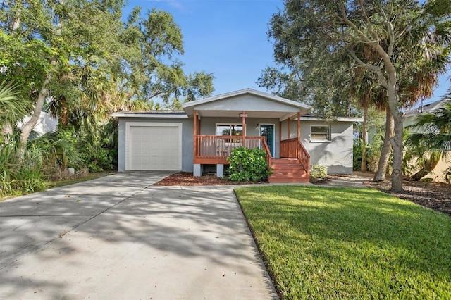 1045 28th Ave S, Saint Petersburg, FL 33705 - view of front facade featuring a porch, stucco siding, a garage, a front yard, and concrete driveway