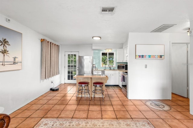1045 28th Ave S, Saint Petersburg, FL 33705 - kitchen with stainless steel appliances, light countertops, white cabinetry, and light tile patterned flooring
