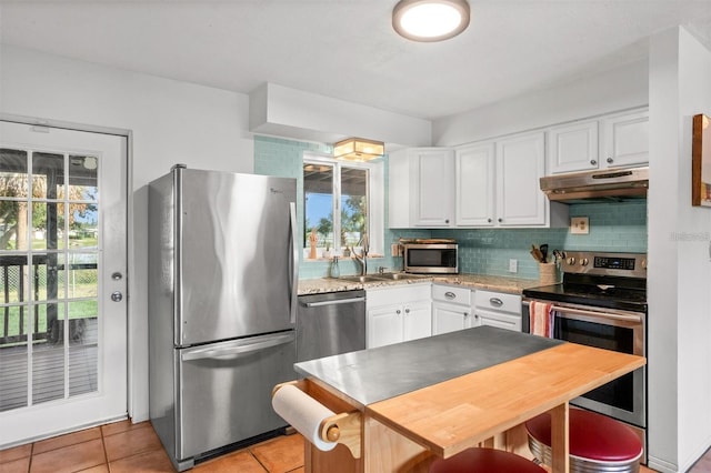 1045 28th Ave S, Saint Petersburg, FL 33705 - kitchen featuring stainless steel appliances, under cabinet range hood, healthy amount of natural light, and light tile patterned floors
