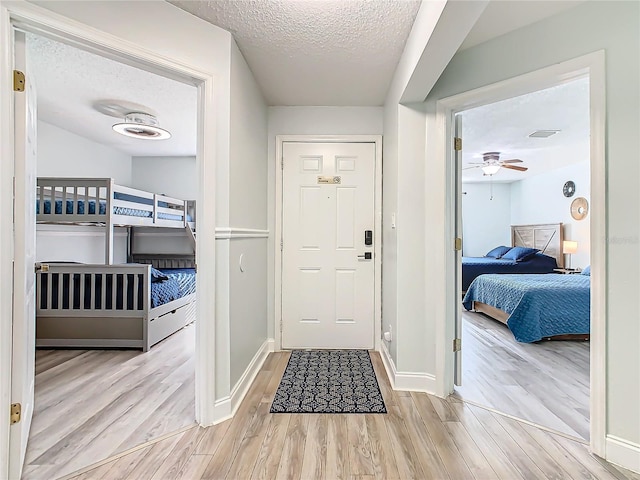 foyer entrance featuring wood finished floors, a textured ceiling, baseboards, and ceiling fan