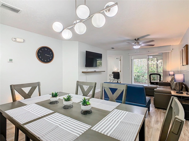 dining space with ceiling fan, light wood-type flooring, and a textured ceiling