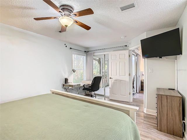 bedroom featuring wood finished floors, a textured ceiling, a desk, and a ceiling fan