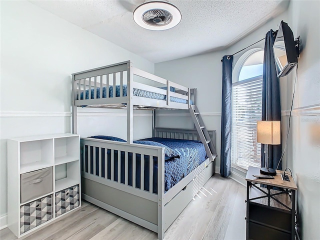 bedroom with wood finished floors, a textured ceiling, and baseboards