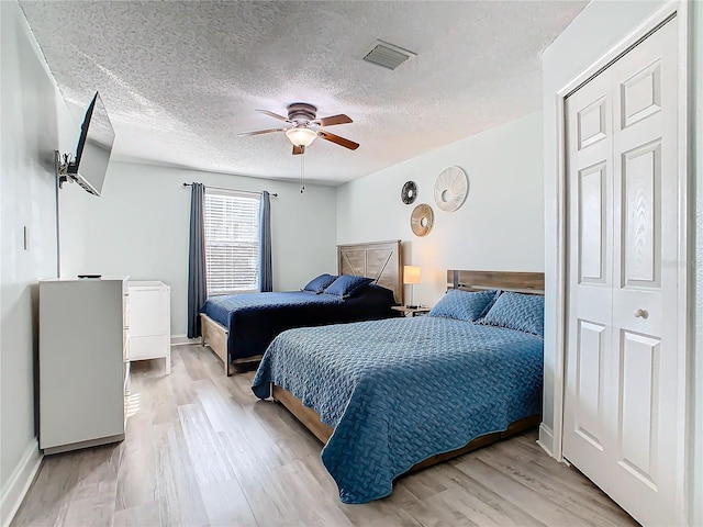 bedroom featuring light wood-style floors, a textured ceiling, a ceiling fan, and baseboards