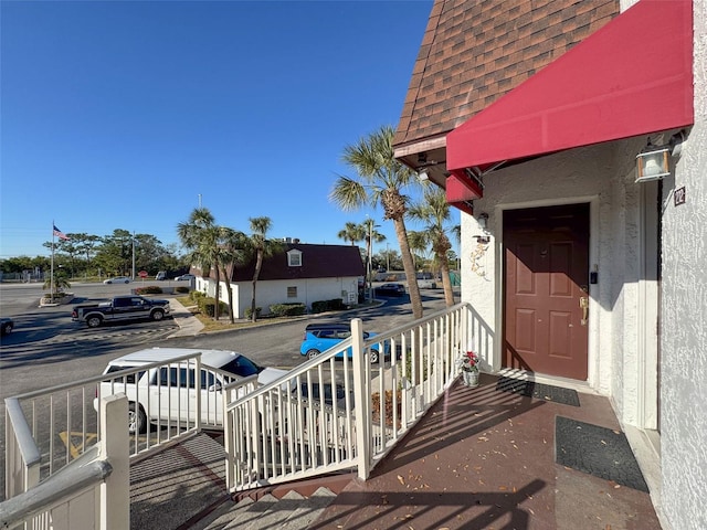 9201 Tudor Dr Unit C212, Tampa, FL 33615 - view of exterior entry with a shingled roof, stucco siding, and a porch