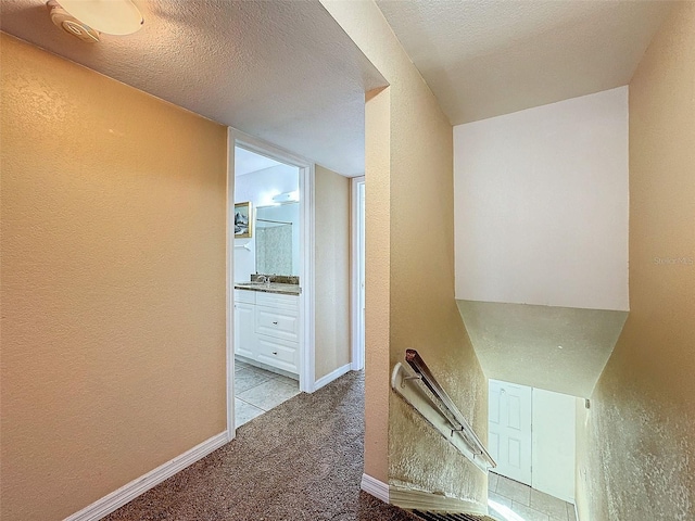 9201 Tudor Dr Unit C212, Tampa, FL 33615 - hall featuring a textured wall, light carpet, an upstairs landing, a sink, and a textured ceiling