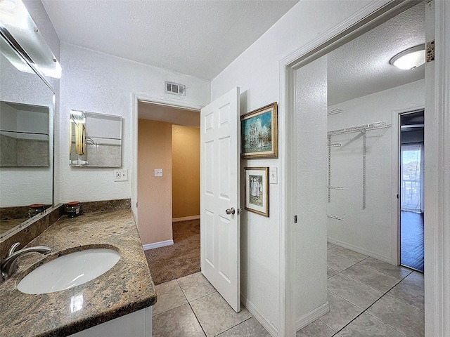 9201 Tudor Dr Unit C212, Tampa, FL 33615 - bathroom featuring tile patterned floors, vanity, a textured ceiling, a walk in closet, and baseboards