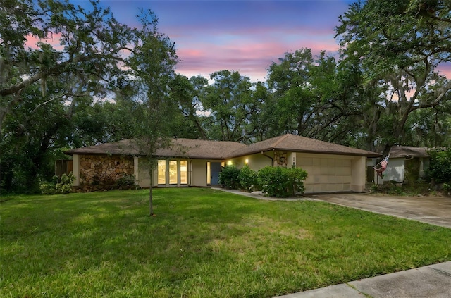 56 Bay Woods Dr, Safety Harbor, FL 34695 - view of front of home featuring an attached garage, a yard, concrete driveway, stucco siding, and french doors