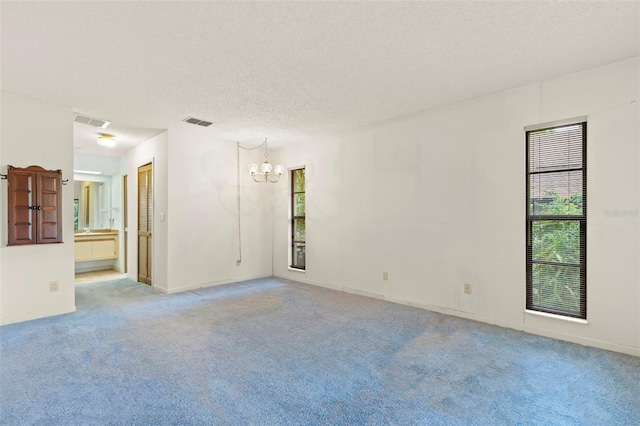 56 Bay Woods Dr, Safety Harbor, FL 34695 - empty room with a chandelier, plenty of natural light, carpet flooring, a textured ceiling, and baseboards