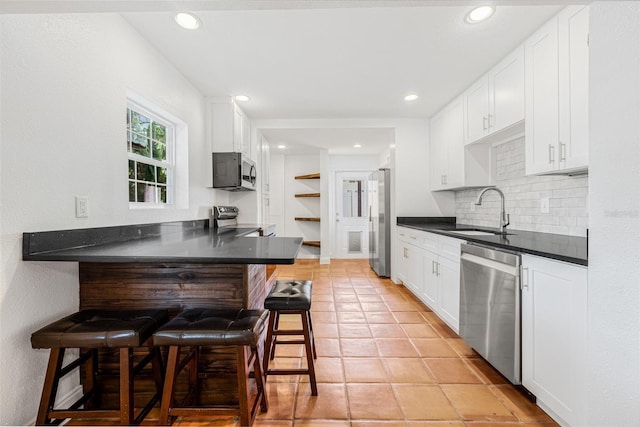 3310 W Ballast Point Blvd, Tampa, FL 33611 - kitchen with appliances with stainless steel finishes, a sink, a kitchen breakfast bar, dark countertops, and backsplash