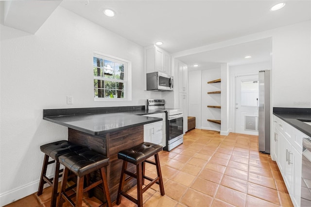 3310 W Ballast Point Blvd, Tampa, FL 33611 - kitchen with stainless steel appliances, dark countertops, white cabinets, recessed lighting, and light tile patterned floors