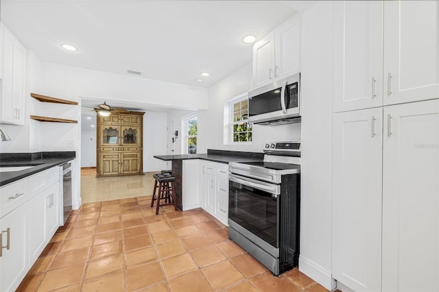 3310 W Ballast Point Blvd, Tampa, FL 33611 - kitchen with appliances with stainless steel finishes, dark countertops, white cabinets, and recessed lighting