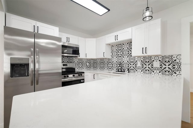5405 S Sellas St, Tampa, FL 33611 - kitchen featuring stainless steel appliances, tasteful backsplash, white cabinets, light countertops, and hanging light fixtures