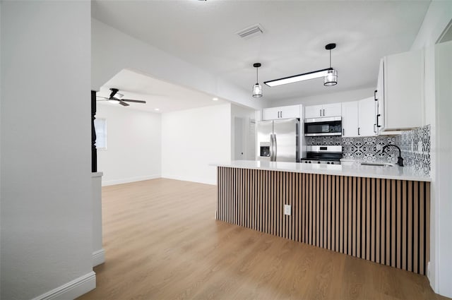 5405 S Sellas St, Tampa, FL 33611 - kitchen featuring appliances with stainless steel finishes, light wood-style flooring, a ceiling fan, and a peninsula