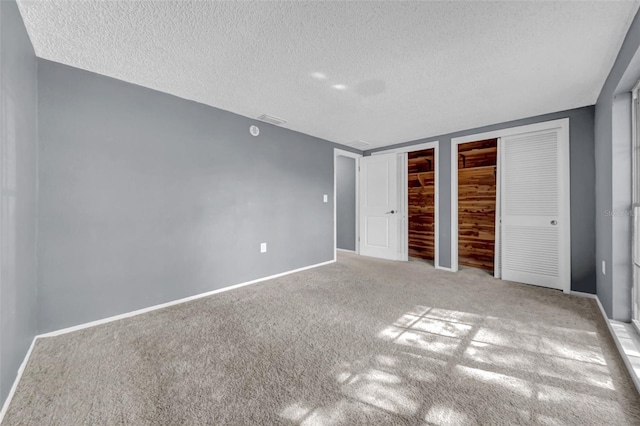 12401 Yorktown Ln, Bayonet Point, FL 34667 - unfurnished bedroom featuring multiple closets, carpet flooring, a textured ceiling, and baseboards