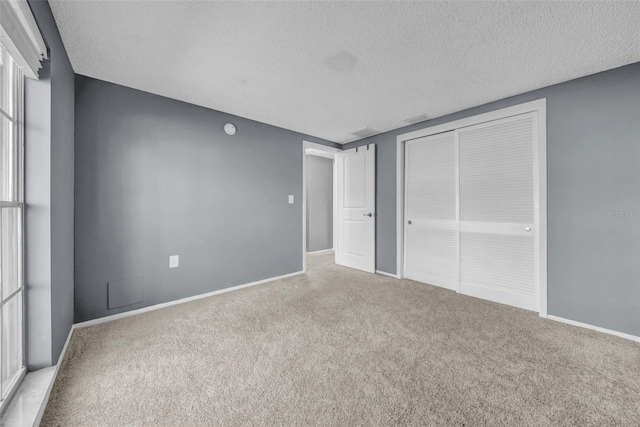 12401 Yorktown Ln, Bayonet Point, FL 34667 - unfurnished bedroom with a textured ceiling, carpet flooring, a closet, and baseboards