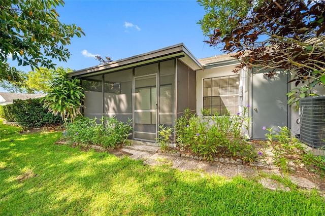 3447 Killdeer Pl, Palm Harbor, FL 34685 - rear view of house featuring a sunroom, central AC unit, a lawn, and stucco siding