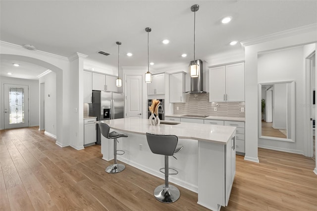 9271 Rally Spring Loop, Wesley Chapel, FL 33545 - kitchen featuring wall chimney range hood, appliances with stainless steel finishes, crown molding, arched walkways, and a sink