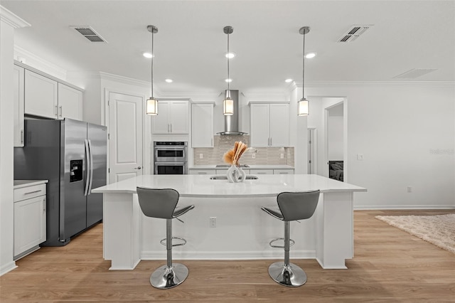 9271 Rally Spring Loop, Wesley Chapel, FL 33545 - kitchen featuring stainless steel appliances, wall chimney range hood, ornamental molding, light wood-style flooring, and light countertops
