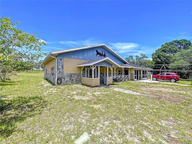 13341 Hexam Rd, Weeki Wachee, FL 34613 - view of front facade with stone siding, a front lawn, and covered porch