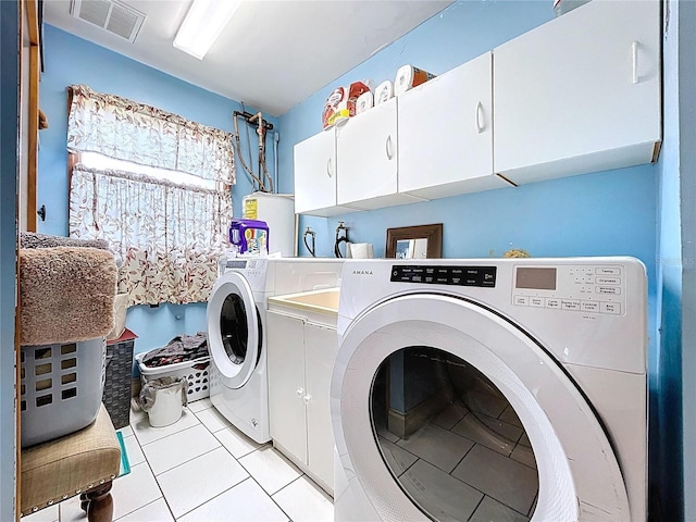 13341 Hexam Rd, Weeki Wachee, FL 34613 - laundry room with cabinet space, washing machine and clothes dryer, water heater, and light tile patterned flooring