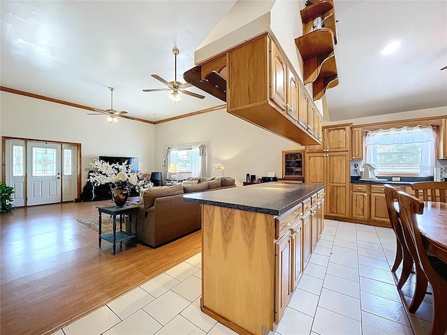 13341 Hexam Rd, Weeki Wachee, FL 34613 - kitchen with dark countertops, a ceiling fan, ornamental molding, light tile patterned floors, and a center island