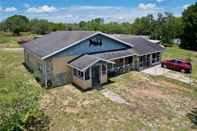 13341 Hexam Rd, Weeki Wachee, FL 34613 - view of front of home featuring a shingled roof, stone siding, a sunroom, a front yard, and view of scattered trees