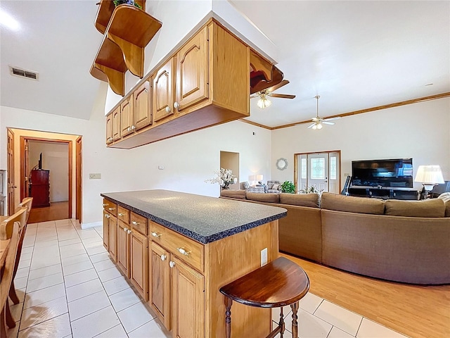 13341 Hexam Rd, Weeki Wachee, FL 34613 - kitchen with a ceiling fan, light tile patterned floors, dark countertops, ornamental molding, and a breakfast bar