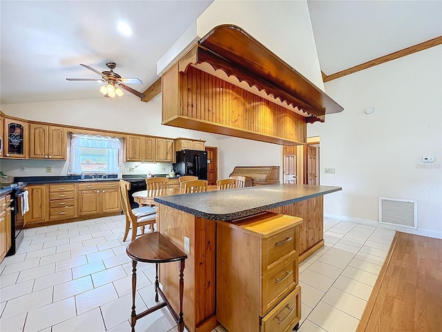 13341 Hexam Rd, Weeki Wachee, FL 34613 - kitchen with black appliances, a breakfast bar, dark countertops, a ceiling fan, and light tile patterned floors