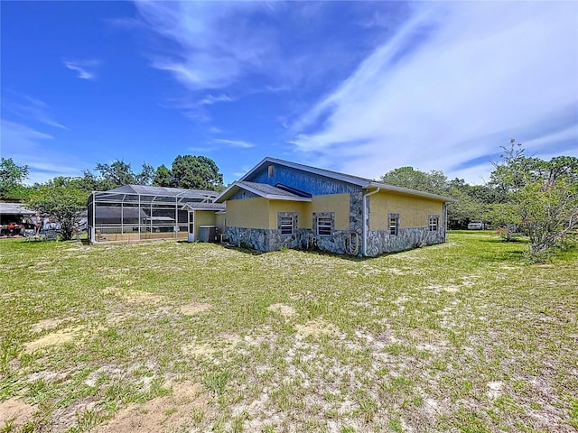 13341 Hexam Rd, Weeki Wachee, FL 34613 - rear view of house featuring stucco siding, a yard, and glass enclosure