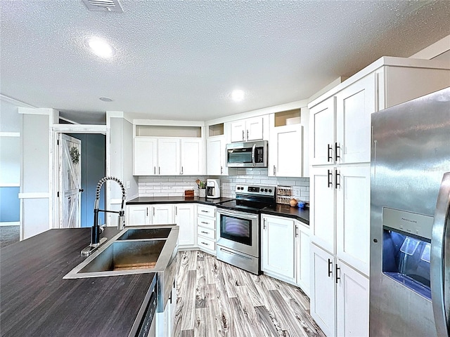 8851 C 469, Center Hill, FL 33514 - kitchen featuring stainless steel appliances, dark countertops, a textured ceiling, white cabinets, and light wood-type flooring